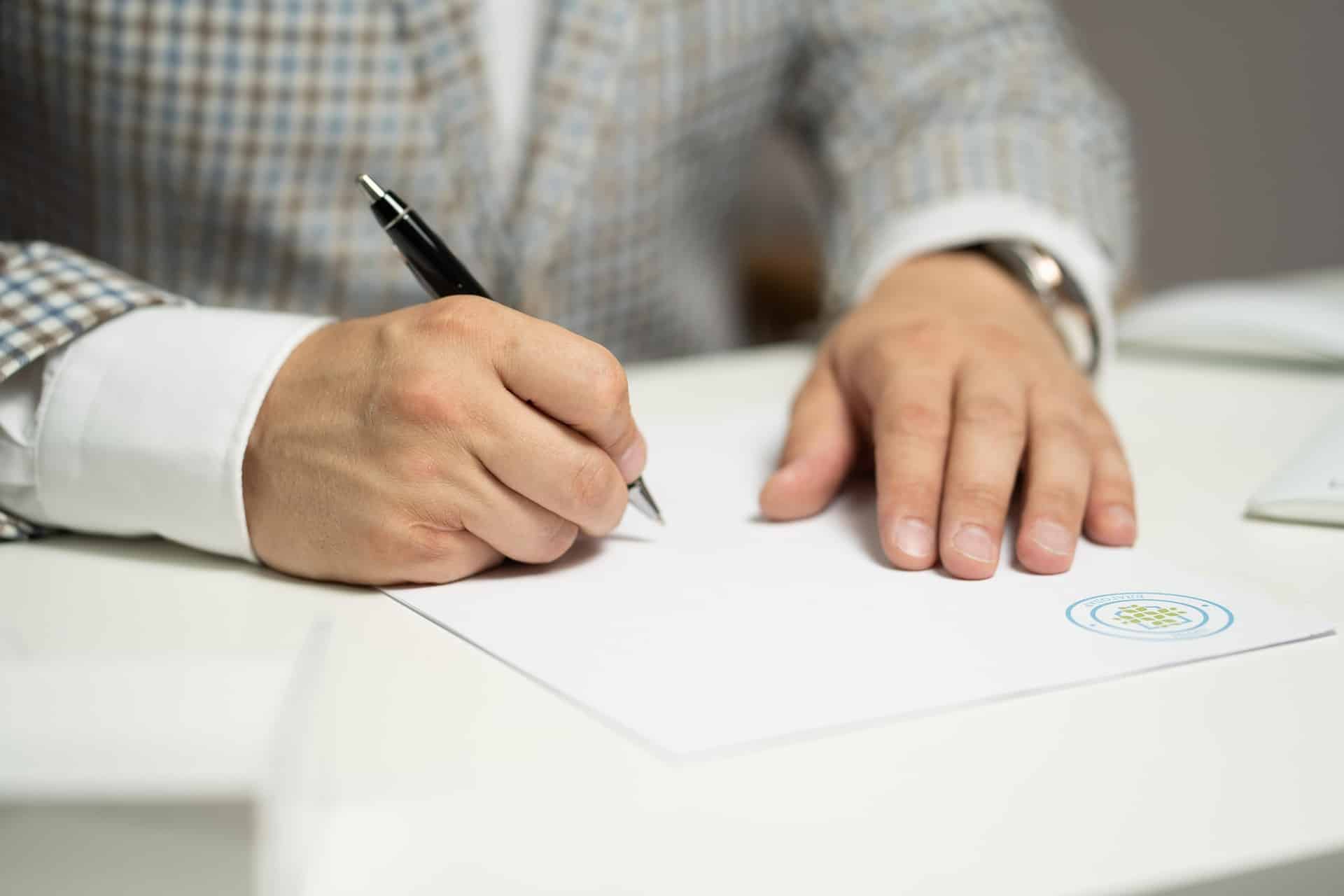 Man zet handtekening op papier. Foto credits: Maximilianovich.