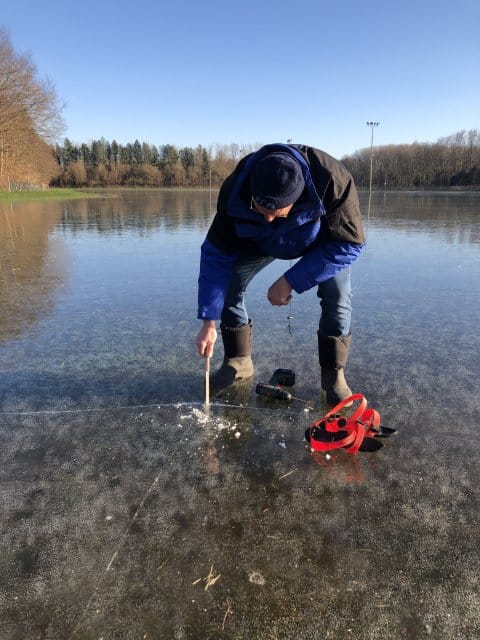 Een medewerker van de ijsbaan in Lelystad controleert de dikte van het ijs.